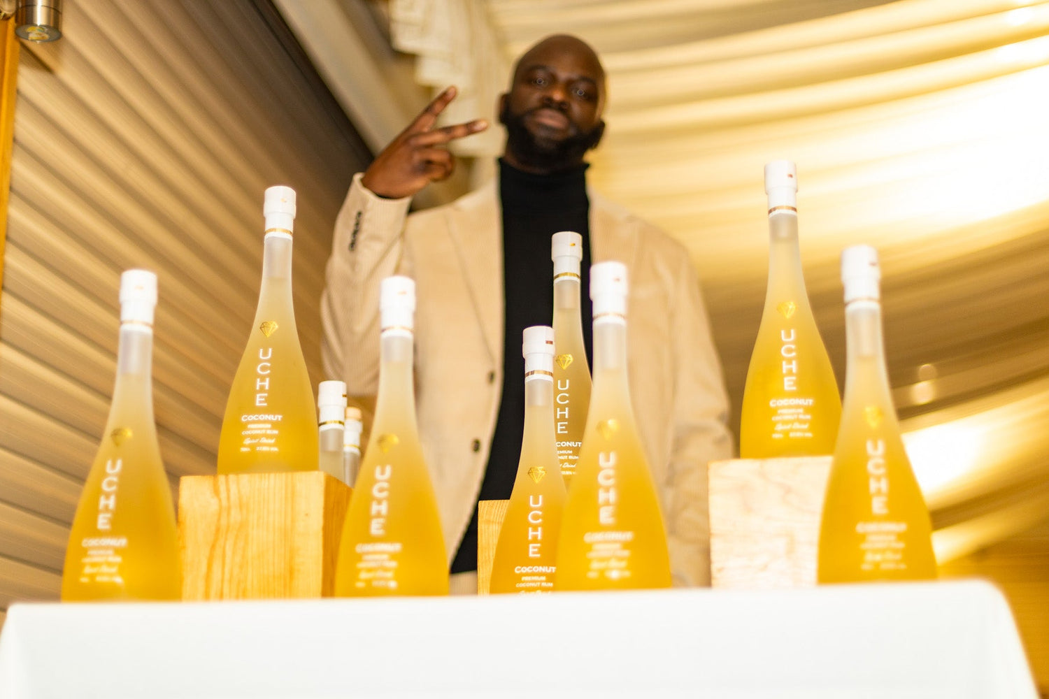 Person standing behind a table with multiple bottles of Uche Rum, with a blurred background